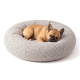 Runder, plüschiger Haustierbett in hellbeige mit einem gepolsterten Design, ausgestattet mit einem kleinen Etikett, das 'PAW WOW' liest.