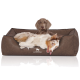 Ein entspannter Hund, der in einem plüschigen braunen Haustierbett mit dem Logo "KNUFFELWUFF" auf der Vorderseite liegt.