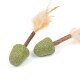 Zwei grüne Katzenspielzeuge in Eichelform mit Feder-Schwänzen, die auf einem weißen Hintergrund liegen.