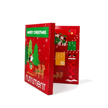 Eine festliche rote Box mit einem Cartoon-Hund, der einen grünen Hut und einen roten Schal trägt und fröhlich mit einem Glockenornament läuft. Der Text lautet 'FROHE WEIHNACHTEN.'