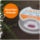 Weißer Behälter mit ARDAP Ameisenködergel mit einer pinken Öffnung, umgeben von grünem Gras, mit dem Text "Neuartiges Ködergel."