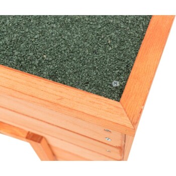 Nahaufnahme eines hölzernen Haustierhauses mit einem grünen strukturierten Dach, das den Holzrahmen und sichtbare Schrauben zeigt.