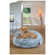 Petit chien bouclé marron couché sur un lit pour animaux en peluche bleu clair dans un salon moderne.