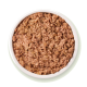 Un bol de nourriture humide pour animaux de compagnie finement hachée, de couleur brun-rosé avec de petits morceaux, sur un fond vert clair.