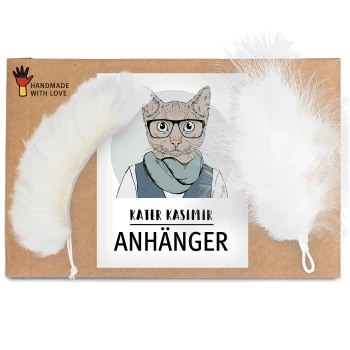 Eine Pappverpackung mit der Aufschrift "KATER KASIMIR ANHÄNGER" mit einer Cartoon-Katzenillustration und zwei weißen Feder-Spielzeugen.