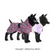 Zwei schwarze Hundemannequins, die bunte Haustierjacken tragen: eine im pink-grünen Leopardenmuster, die andere aus glänzendem reflektierendem Material.