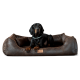 Ein schwarz-brauner Hund, der auf einem plüschigen, braunen Haustierbett mit lederähnlicher Textur entspannt, mit einem kleinen Holzschild, das "terlanda" liest.
