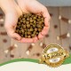 Hände halten einen Haufen brauner Haustierfutter-Kibble, mit einem Abzeichen, das 'Bewährte Qualität seit über 15 Jahren' und 'Beste Qualität' angibt.