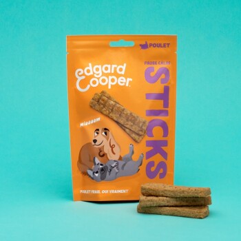 Friandises pour chiens Edgard Cooper dans un sac orange, avec des chiens de dessin animé et le texte "STICKS" et "poulet." Trois bâtonnets sont devant.