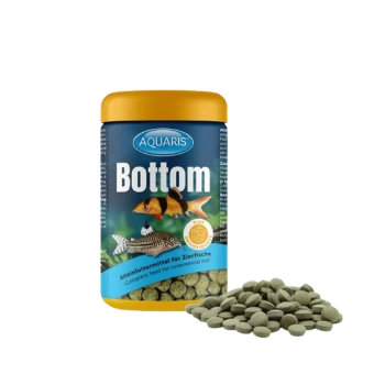 Aquaris Bottom Fischfutter in einem gelben Behälter, mit einem Teller grüner, tablettenförmiger Pellets daneben.