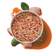Schüssel mit Haustierfutter, die kleine, rosafarbene Kroketten zeigt, umgeben von frischen Zutaten wie Karotten, Apfelscheiben, Spinat und Hähnchen.