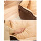 Ein gemütliches Haustierbett mit einem braunen Äußeren und einem weichen beigen Inneren, mit einer Hand, die in das plüschige Kissen drückt.