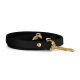 Schwarze Hundeleine mit goldenen Beschlägen, ordentlich auf einem weißen Hintergrund aufgerollt.