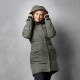 Eine Person trägt eine grüne, kapuzenartige Winterjacke mit mehreren Taschen und steht vor einem grauen Hintergrund.