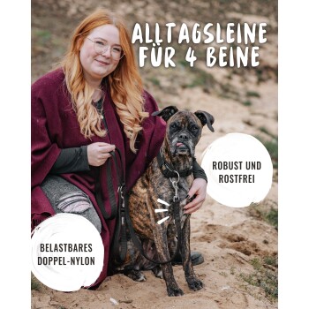 Eine Frau in einem kastanienbraunen Poncho sitzt mit einem gestromten Hund. Der Text lautet "Alltagsleine für 4 Beine," "Belastbares Doppel-Nylon," "Robust und Rostfrei."