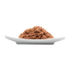 Un tas de nourriture pour animaux de compagnie brune sur une assiette blanche, montrant son apparence texturée.