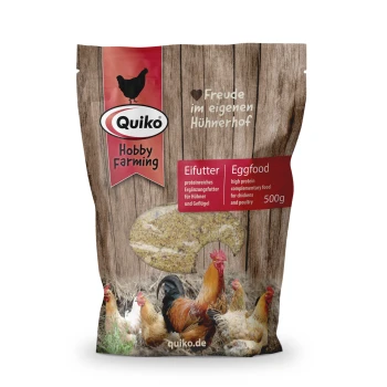Emballage d'aliment pour œufs Quiko Hobby Farming sur un fond en bois brun, montrant des poules et un texte bilingue sur un aliment avicole riche en protéines.