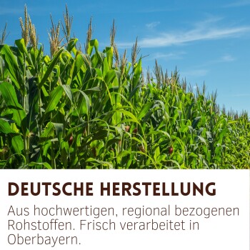 Maisfeld unter blauem Himmel mit dem Text „Deutsche Herstellung“ und Beschreibung hochwertiger regionaler Rohstoffe, verarbeitet in Oberbayern.