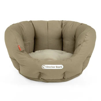 Ein gemütliches, rundes Tierbett in neutralem Beige mit einem weichen, plüschigen Innenraum und einem sichtbaren "Doctor Bark"-Logo an der Seite.