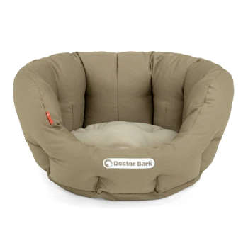 Ein gemütliches, rundes Tierbett in neutralem Beige mit einem weichen, plüschigen Innenraum und einem sichtbaren "Doctor Bark"-Logo an der Seite.