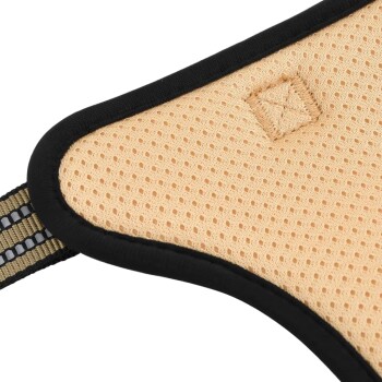 Nahaufnahme eines beigen, atmungsaktiven Haustiergeschirrs mit schwarzem Rand und einem gestickten Patch, das seine Netzstruktur und den verstellbaren Riemen zeigt.