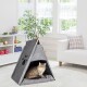 Eine flauschige Katze sitzt in einem grauen Filz-Haustier-Tipi mit einem Pfotenabdruckdesign, in einem hellen Raum mit großen Fenstern und einer gemütlichen Atmosphäre.