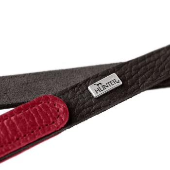 Nahaufnahme eines schwarzen und roten Lederhundehalsbandes mit einem silbernen "HUNTER"-Logoanhänger.