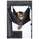 Eine flauschige braun-schwarze Katze, die in einer grauen Hängematte an einem Katzenbaum entspannt, mit einem neugierigen Ausdruck.