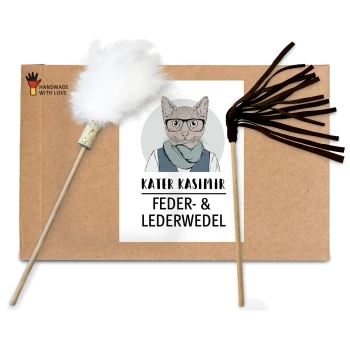 Kartonverpackung mit zwei Katzenspielzeugen: einem Federwedel und einem Lederquast, beschriftet mit "KATER KASIMIR FEDER- & LEDERWEDEL."
