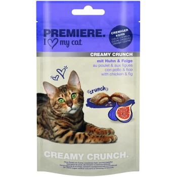 Eine Bengal-Katze mit grünen Augen ruht neben einem Paket von 'Premiere I Love My Cat Creamy Crunch' Leckerlis, mit Huhn und Feige.