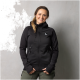 Eine Person trägt eine schwarze Jacke mit Reißverschluss und Kapuze mit dem Logo "DOG" auf der linken Brust, steht vor einem grauen Hintergrund.