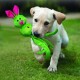 Un chiot Labrador jaune joueur porte un jouet lapin vert vif avec des oreilles roses dans sa bouche, posé sur une pelouse herbeuse.