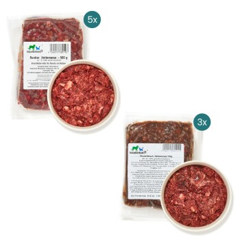 Zwei Rohfutterpakete für Haustiere mit der Aufschrift "Rentier, 500 g" und "Pferdefleisch, 500 g," mit Schalen von Hackfleisch davor.