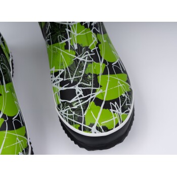 Nahaufnahme von lebhaft grünen und schwarzen Haustierstiefeln mit einem verspielten abstrakten Design und weißen Linien, ideal für den Außeneinsatz.