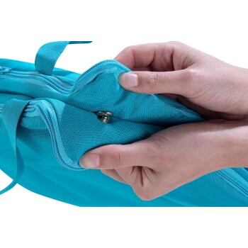 Hände öffnen eine blaue Stoff-Tiertragetasche mit Druckknopfverschluss und Reißverschluss vor weißem Hintergrund.