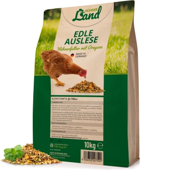 Braune Henne, die neben einem Haufen Hühnerfutter auf einem Sack mit der Aufschrift "Hühner Land Edle Auslese Hühnerfutter mit Oregano," 10kg steht.