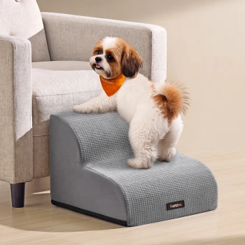 Flauschiger weiß-brauner Hund mit orangefarbener Bandana auf grauen Haustiertreppen neben einem Sessel; Etikett: 'feandrea'.