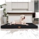 Ein großer weißer Hund liegt auf einem schwarzen Hundebett in einer modernen Küche mit hellen Holzböden und minimalistischer Gestaltung.