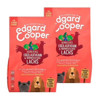 Zwei Tüten Edgard Cooper Senior-Hundefutter mit rotem Hintergrund, die Huhn, Lachs, Brokkoli, Heidelbeeren und Cranberries zeigen.