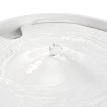 Eine Nahaufnahme eines Haustier-Wasserbrunnens mit plätscherndem Wasser und einem kleinen Spritzer, der sein sauberes, weißes Design zeigt.