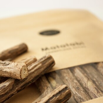 Natürliche Kausticks für Haustiere, die vor einer braunen Papiertüte mit dem Aufdruck 'Mastihali' und einem Logo angeordnet sind, und ein rustikales Design zeigen.