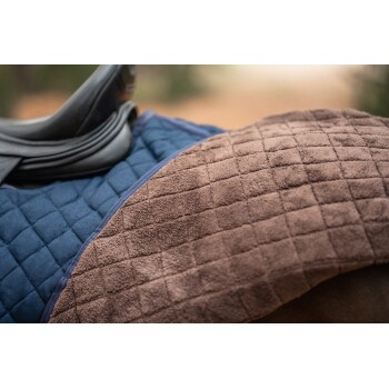 Nahaufnahme eines Pferdesattels mit einer navyblauen, gesteppten Stoffseite und einer weichen braunen Fleece-Seite.