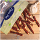 Eine Tüte mit Haustierleckereien mit der Aufschrift "Furta Pet" und einem Logo, mit verdrehten Fleischsticks, die auf einer Holzoberfläche verstreut sind.