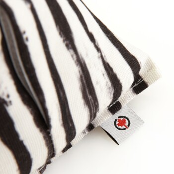 Nahaufnahme eines Haustierbettes mit einem schwarz-weißen gestreiften Design, mit einem kleinen Etikett, das ein rotes Ahornblattlogo zeigt.