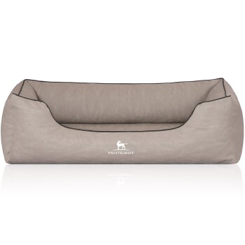 Ein weiches, beiges Hundebett mit runder Form und schwarzem Rand, auf dem das Markenlogo "KNUFFELWUFF" prominent angezeigt wird.