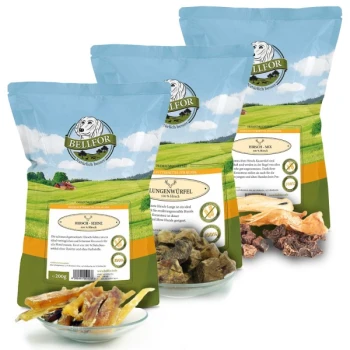 Drei Säcke BELLFOR-Haustierleckereien, beschriftet mit 'Hirsch-Mix', 'Hirsch-Würfel' und 'Hirsch-Snacks', mit einer Schüssel assortierter Trockenfleischstücke davor.