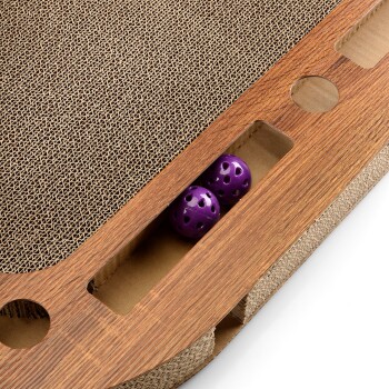 Eine Nahaufnahme eines Katzenkratzbaums aus natürlichem Holz und Wellpappe, mit zwei lila Bällen, die in einem Schlitz versteckt sind.