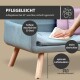 Modernes Wohnzimmer mit einem hellblauen Sofa, rosa Kissen, einem schwarzen Drahtstuhl mit weißem Fellüberwurf und pflanzenmotivierter Wandkunst.