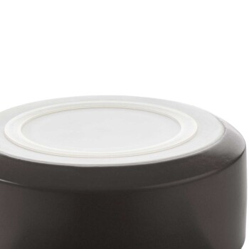 Eine Nahaufnahme des Bodens einer dunklen Keramik-Hundeschüssel mit einem weißen Rand, die eine glatte, glänzende Oberfläche zeigt.