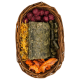 Ein geflochtener Korb, gefüllt mit verschiedenen Tierleckereien: dunkelgrüner Kräuterblock, orangefarbene getrocknete Gemüsescheiben, gelbes Heu und lila Beerenbälle.
